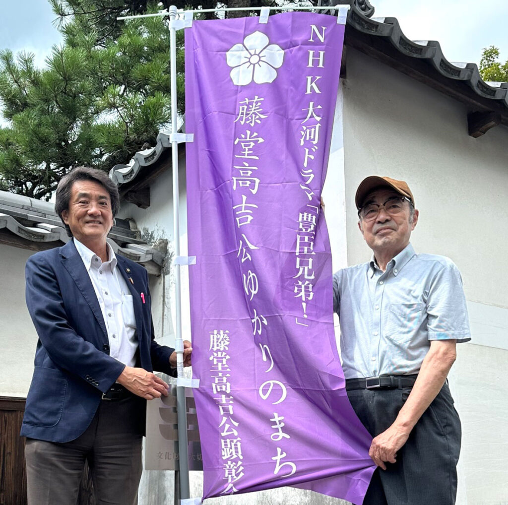 藤堂高吉公顕彰会の幟を持つ名張市長と藤堂高吉公顕彰会の会長角田勝